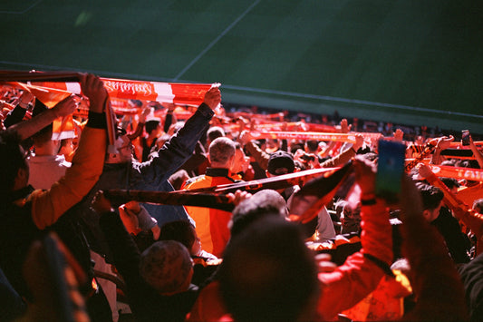 Supporters tillen rode sjaals omhoog in een vol stadion tijdens een intense WK-avond